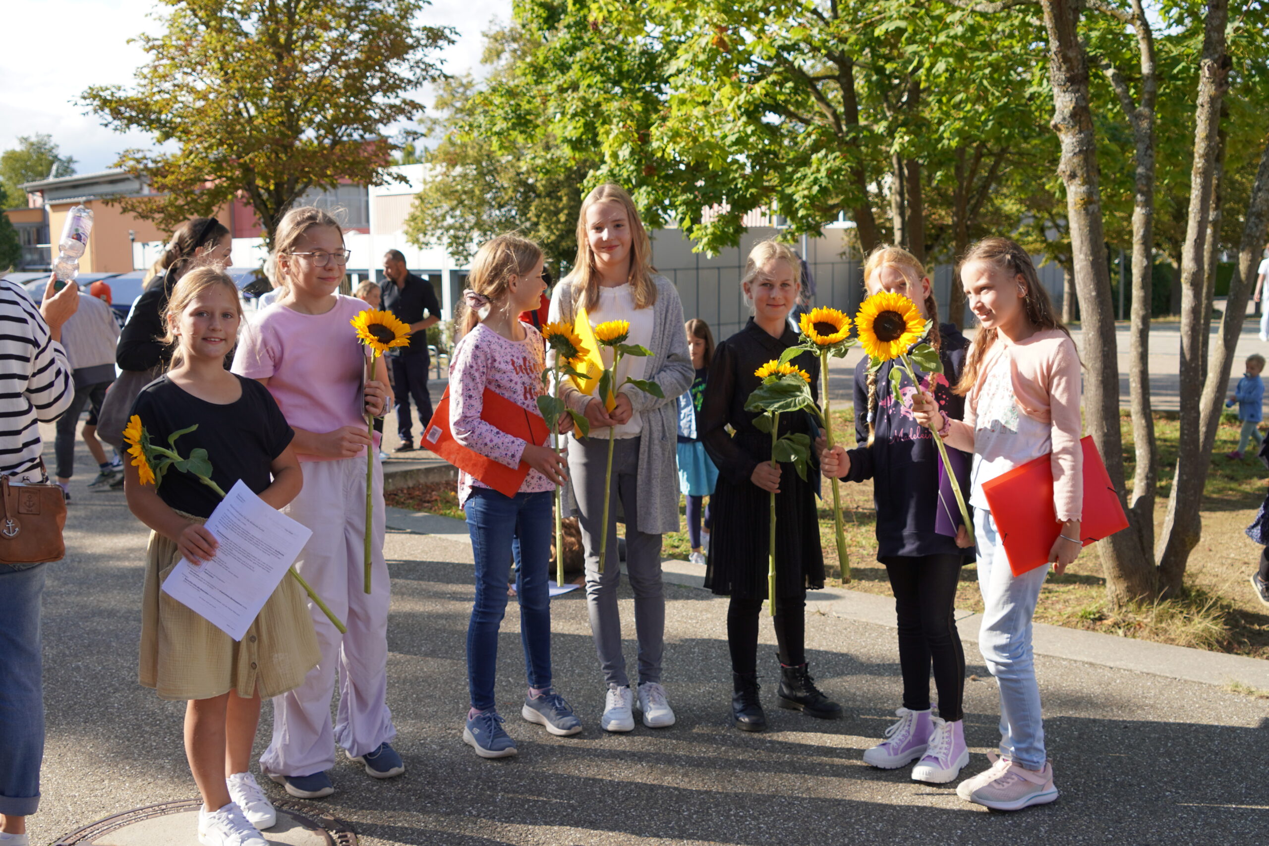 einzelne Kinder am Einschulungstag mit Sonneblume
